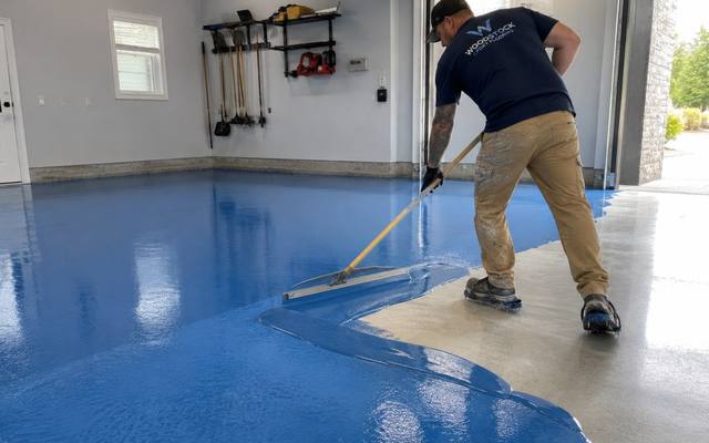Installer spreading blue epoxy across a garage floor in Cambridge